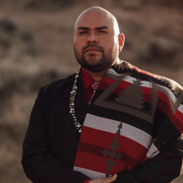 Brian Melendez, President & CEO of Tribal Minds, Inc. image of man with traditional wardrobe and blanket with Paiute black and red colors.